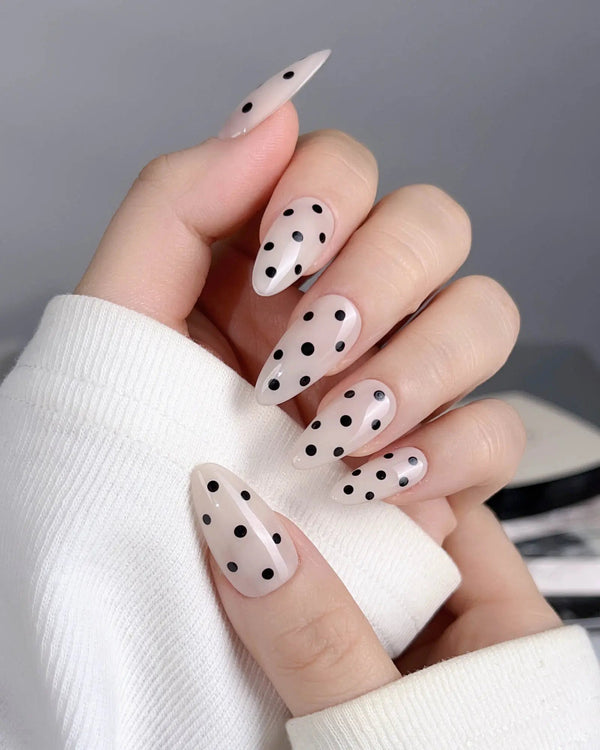 Glossy nude almond nails with black dots