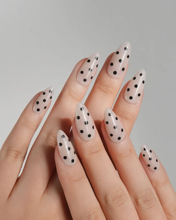 Close-up of Dot Noir press-on nails with nude base and black retro polka dots