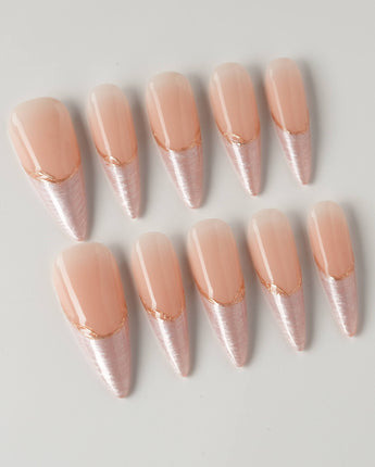 Your Glow in long stiletto shape with nude French tips, cat-eye shimmer, and gold detail