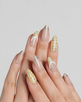 Tweed Light press-on nails with nude base, gold glitter French tips, yellow plaid, and lace trim