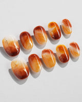 Close-up of Onyx Shine nails with amber marble swirls and polished translucent depth