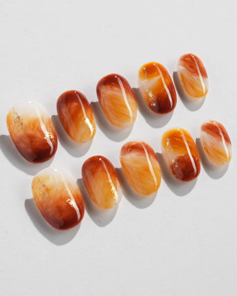 Close-up of Onyx Shine nails with amber marble swirls and polished translucent depth