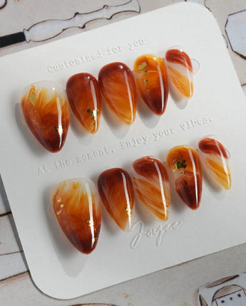 Onyx Shine press-ons with amber marble swirls, dark depth, and polished gel shine