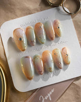 Pastel Relic press-on nails with iridescent champagne glow and refined gold starburst art