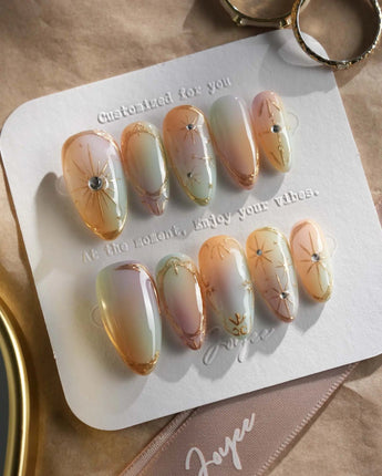 Pastel Relic press-on nails with iridescent champagne glow and refined gold starburst art