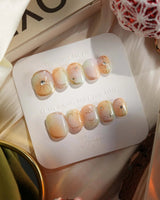 Pastel Relic nail close-up with champagne gradient, gold strokes, and glossy gel surface