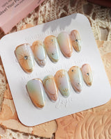 Pastel Relic nail detail with iridescent milky color, gold accents, and glossy gel finish