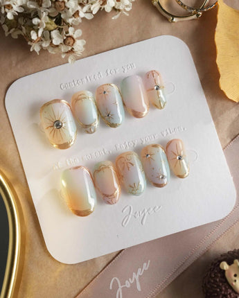 Pastel Relic press-on nails with pearly pastel base, gold linework, and polished gel shine