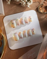 Pastel Relic nails with champagne-toned gradient, fine gold accents, and glossy finish