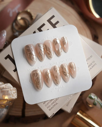 Plume handmade press-on nails featuring Elegant Nude, Brushed Gold Foil Feathers & Fluid Textures.