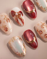Coquette Red press-on nails with deep red chrome, gold outlines, bows, and rose accents