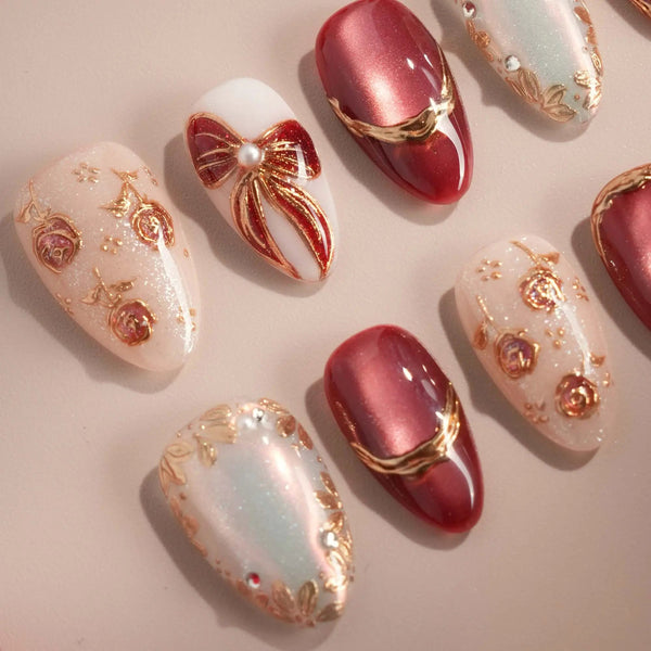 Red cat-eye nails with gold roses and 3D bow