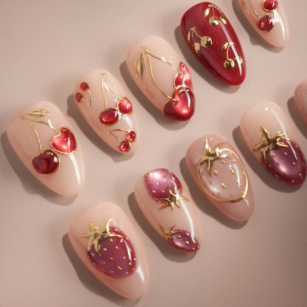 Red and gold cat-eye nails with cherry and strawberry accents