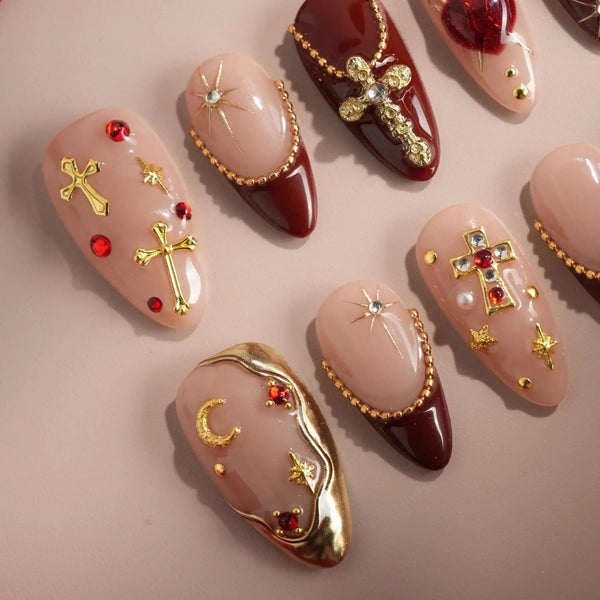 Red and gold press-on nails with cross and gem accents