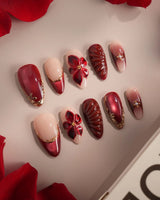 Close-up of Lily Rouge press-on nails with red cat-eye French tips, gold outlines and 3D flowers