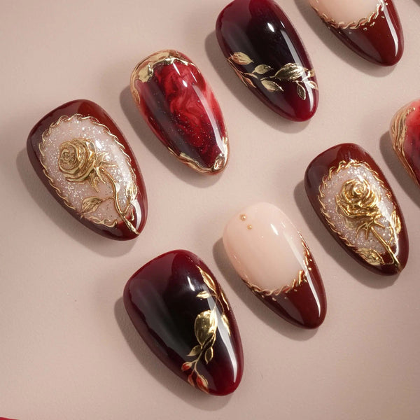 Gilded Merlot press-on nails with deep red cat-eye, nude French tips and gold rose reliefs