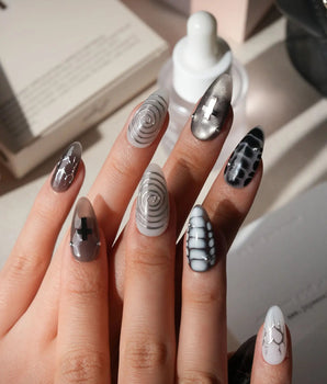 Relic press on nails in smoke grey and bone white with black marble veins, a silver starburst, a sculpted silver cross and a spiral - image 2
