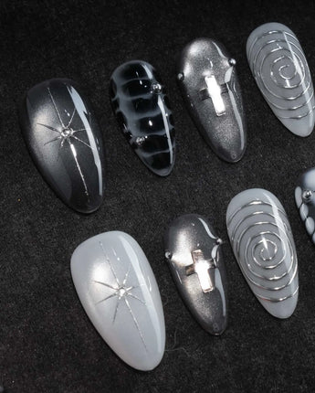 Relic press on nails in smoke grey and bone white with black marble veins, a silver starburst, a sculpted silver cross and a spiral - image 1