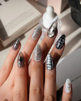 Relic press on nails in smoke grey and bone white with black marble veins, a silver starburst, a sculpted silver cross and a spiral - image 2