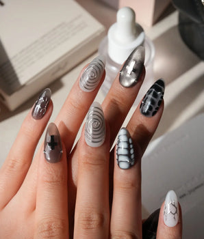 Relic press on nails in smoke grey and bone white with black marble veins, a silver starburst, a sculpted silver cross and a spiral - image 2