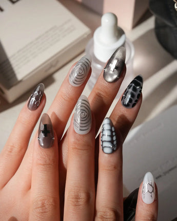 Relic press on nails in smoke grey and bone white with black marble veins, a silver starburst, a sculpted silver cross and a spiral - image 2