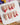 Nude base nails with red flame swirls and metallic star embellishments	