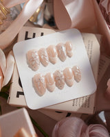 Satin Dress nail art close-up showing nude pink pearl sheen 3D floral ribbon embossed details