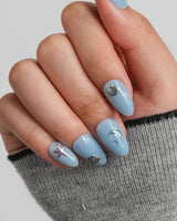 Sea Chrome close-up of metallic sea creature charms on glossy blue gel nails