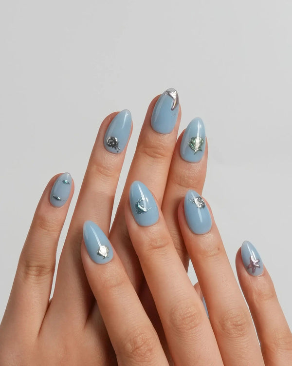 Sea Chrome extra short almond nails with cornflower-blue base and metallic ocean charms