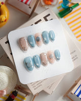 Shell Money extra short almond nails with metallic shell charms and beach-luxe shine