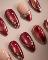 Molten Rouge nail art close-up showing deep red cat eye nude base gold outline crystal accents details