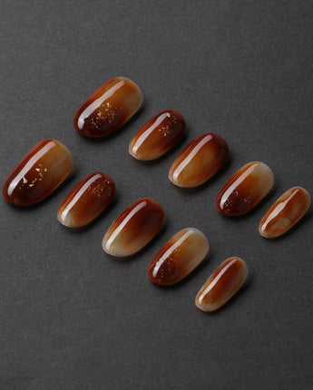 Onyx Shine in short oval shape with amber marble nails and glossy gel depth