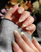 Silk Glow press-on nails with light gold cat-eye shimmer and delicate gold French wire