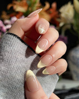Close-up of Silk Glow nails with light gold cat-eye finish and gold wire detail