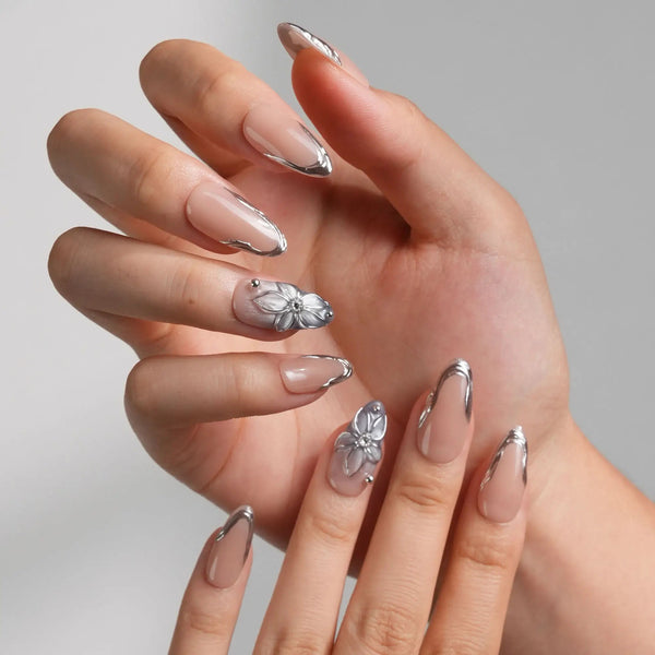 Silver Shore medium almond nails with nude base, sculpted silver French tips, and 3D metallic flower