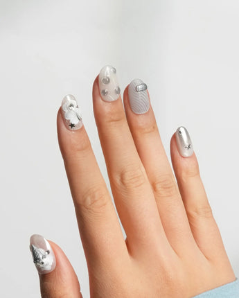 Silver Spoon close-up of silver cutlery and butterfly charms on grey press-on nails