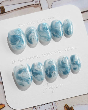 Starry River extra short oval nails with watery blue swirls and silver shimmer accents