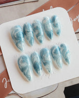 Starry River medium stiletto nails with fluid blue marble and shimmering cat-eye effect