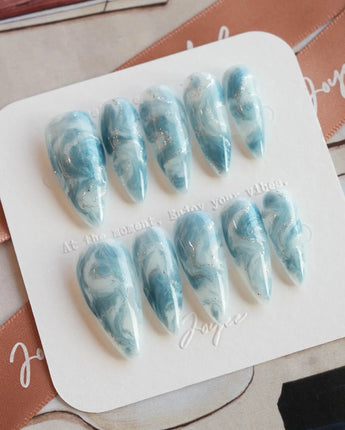 Starry River medium stiletto nails with fluid blue marble and shimmering cat-eye effect