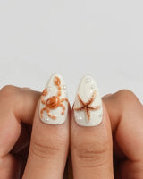 Sun Fossil medium almond press-on nails with warm 3D beach shells and pearls