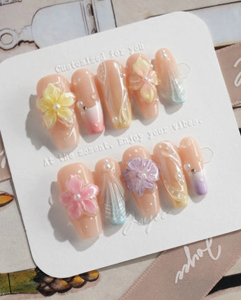 Sunbathing golden-hour nails with iridescent nude base and sculpted floral shine