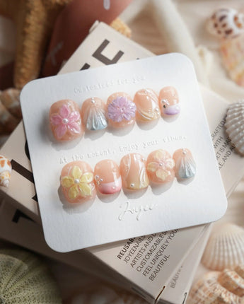 Sunbathing extra short squoval nails with nude pastels, 3D florals, and shells