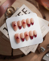 Sweet Venom press-on nails in short almond shape — Ruby Red French, gold Outlines, 3D Red Hearts & Shimmering Lines.