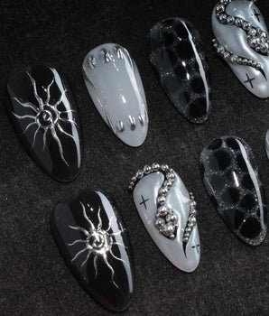 Talisman press on nails with a raised silver spiral sun on black, chrome white, glitter web print and a pearl nail crossed with silver beads - image 1
