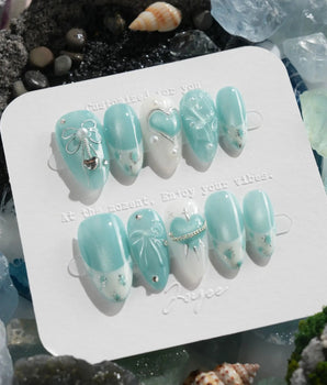 Exuma Blue pastel turquoise nails with sculpted bows, hearts, butterflies, and pearl accents