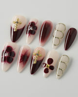 Tip Burgundy Nails in medium stiletto shape with red tips, gold cross, and flower details