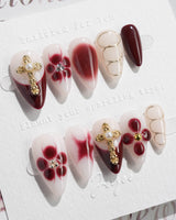 Tip Burgundy Nails in short stiletto shape with burgundy tips, gold cross, and floral accents