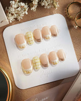 Tweed Light press-ons featuring golden plaid French tips and glossy neutral gel finish
