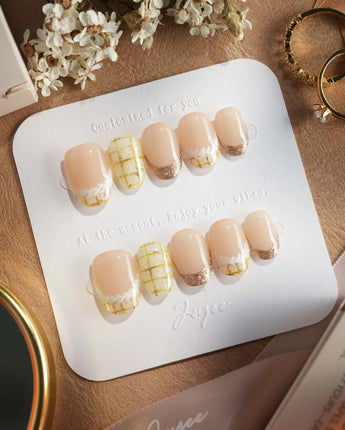 Tweed Light press-ons featuring golden plaid French tips and glossy neutral gel finish