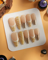 Tweed Light nail close-up with soft nude polish, yellow plaid art, and gold glitter tips